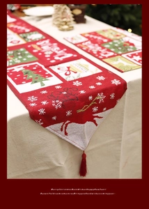 Close-up of red Christmas table runner with festive elk patterns and red tassel details