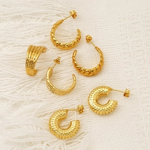 Three pairs of vintage gold hoop earrings with twisted and textured patterns on white fabric
