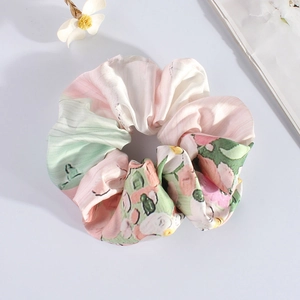 Detail of a floral satin scrunchie with pastel watercolor patterns on a white background