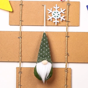 Detail of a green knitted Christmas gnome ornament with white heart pattern and long beard