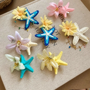 Detail of fabric flowers and raffia starfish hair clips with elegant bohemian textures
