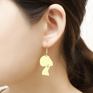 Close-up of gold stainless steel earrings featuring an artistic African woman silhouette