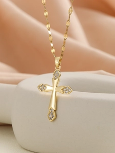 Macro shot of gold cross pendant with cubic zirconia inlay on a grey ceramic vase