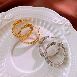 Three-layer twisted metal hoop earrings in gold and silver with beaded texture detail