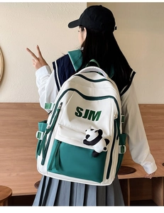 Back view of a white and green vintage campus backpack with cute panda charm accessory