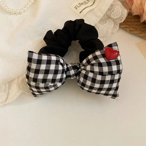 Detailed macro view of black and white checkered bow hair tie with red heart button