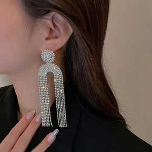 Exaggerated silver U-shaped tassel earrings with sparkling rhinestones worn by a model