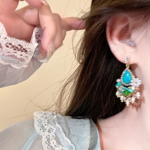Macro detail of bohemian teardrop turquoise earring with floral beads and pearls