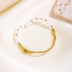Elegant gold titanium steel bracelet with white pearls on a luxury silk background