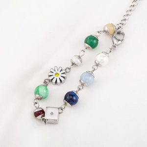 Charming beaded bracelet featuring daisy charm, silver cube, and colorful pearls