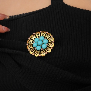Detail of vintage flower brooch with blue beads and pink crystals on black fabric
