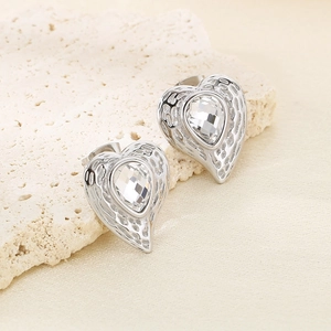 Dettaglio di orecchini a cuore in argento con metallo strutturato e grandi cristalli