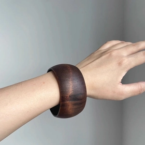 Macro shot of a wide bohemian dark brown wooden bangle with natural grain texture