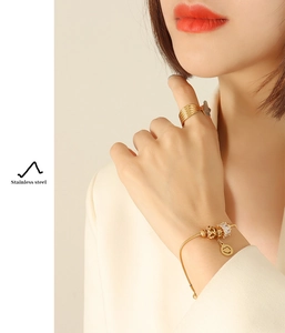 Detail of 18K gold-plated stainless steel slider bracelet and multi-layer ring for women