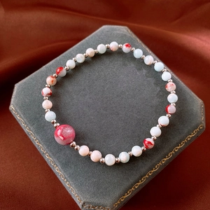 Detail of Shoushan stone beaded bracelet with red cracked main bead on gray jewelry stand