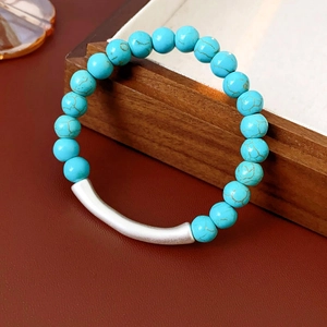 Gros plan du bracelet en perles turquoise avec tube argenté sur fond en cuir