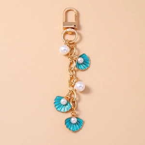 Detailed close-up of gold keychain with blue enamel shells and embedded white pearls