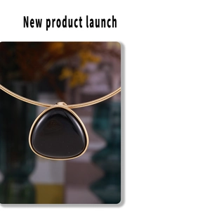 Macro detail of geometric black onyx pendant on gold plated snake chain necklace