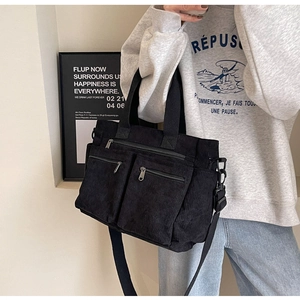 Detailed shot of black corduroy tote bag featuring adjustable strap and zipper pockets