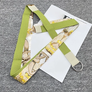 Detail of canvas and silk scarf belt featuring silver D-rings on a grey texture background