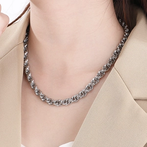 Minimalist silver stainless steel twist chain necklace worn with a stylish beige blazer
