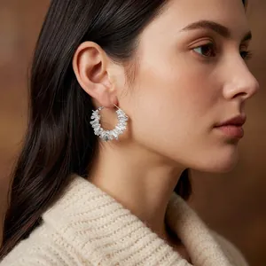 Boucles d'oreilles créoles géométriques argentées irrégulières portées par un mannequin