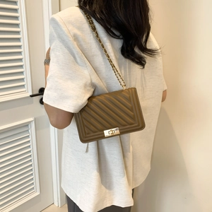 Detail of brown quilted leather shoulder bag with gold metal twist lock and chain strap