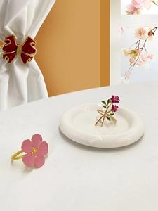 Detail of metal napkin rings featuring painted red bow and pink floral designs