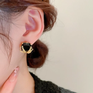 Detail of dark square crystal earring with golden wheat ear metal texture in macro view