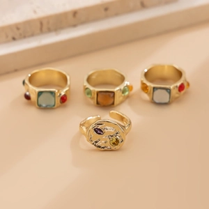 Set of four gold-plated rings with colorful gemstones and textured hammered finish