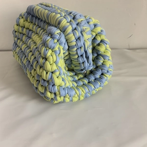 Detailed knit texture of a handmade blue and lime green striped cotton yarn bag