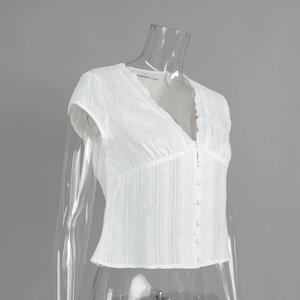 Detail of white V-neck shirt featuring lace trim, ribbed fabric texture and button closure