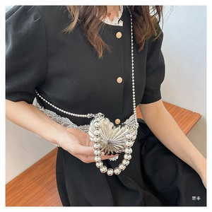Silver heart-shaped mini bag with textured metallic finish and pearl chain worn by a model