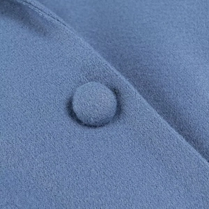 Close-up of a blue wool fabric jacket featuring a matching cloth-covered button detail