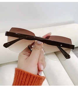 Close-up of rimless gradient sunglasses featuring gold metal hinges and a brown top bar