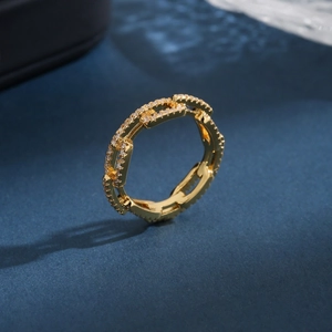 Minimalist 18K gold chain link ring with pavé zircon stones on a deep blue background