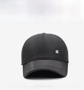Detail view of quilted baseball cap with metal logo and faux leather brim in black