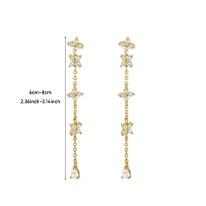Detail of long gold tassel earrings with crystal flower petals and teardrop charm
