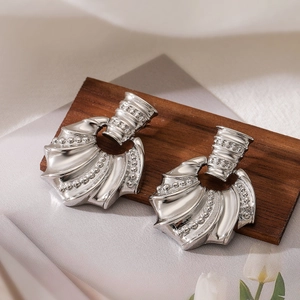 Modern silver irregular geometric fan earrings with beaded texture on dark wood background