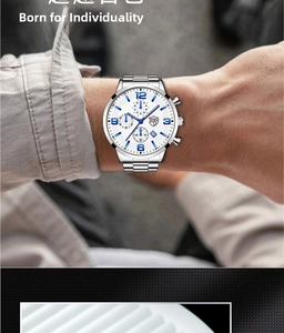 Detail of man wearing a silver stainless steel watch with blue numerals and calendar dial