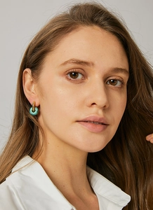 Close-up of vintage golden hoop earrings with turquoise stones worn by a model