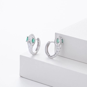 Macro detail of S925 silver snake earrings with white enamel and green gemstones