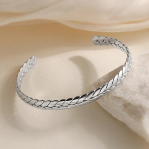 Silver open cuff bracelet with wheat weave texture on a minimalist stone background