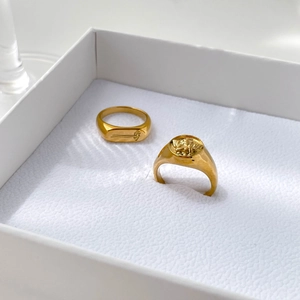 Close-up of gold signet rings with vintage angel relief and floral engraving in a gift box