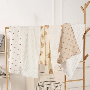 Close-up of baby blankets featuring cherry, bear, and rainbow prints with 3D dotted fleece