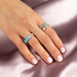 Detailed view of three-piece gold ring set with turquoise gems and zircon on purple silk