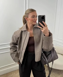 Détail d'une veste en tweed taupe avec plis élégants et fermeture éclair métallique