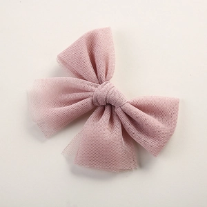 Detailed view of pink mesh tulle bow hair clip on a neutral soft beige background