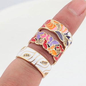 Macro view of stacked gold-plated enamel rings with colorful patterns and zircons