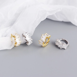 Macro detail of rectangular zircon stones on gold and silver irregular earring clips